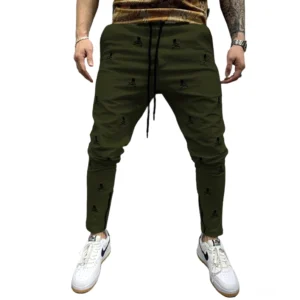 Armeegrüne All-Over-Totenkopf-bedruckte Gothic Lace-Up Röhrenhose für Herren, demonstriert schlanke alternative Mode Silhouette mit armeegrüner Basis und schwarzem Skull-Print, Schnürweste und seitliche Reißverschlüsse
