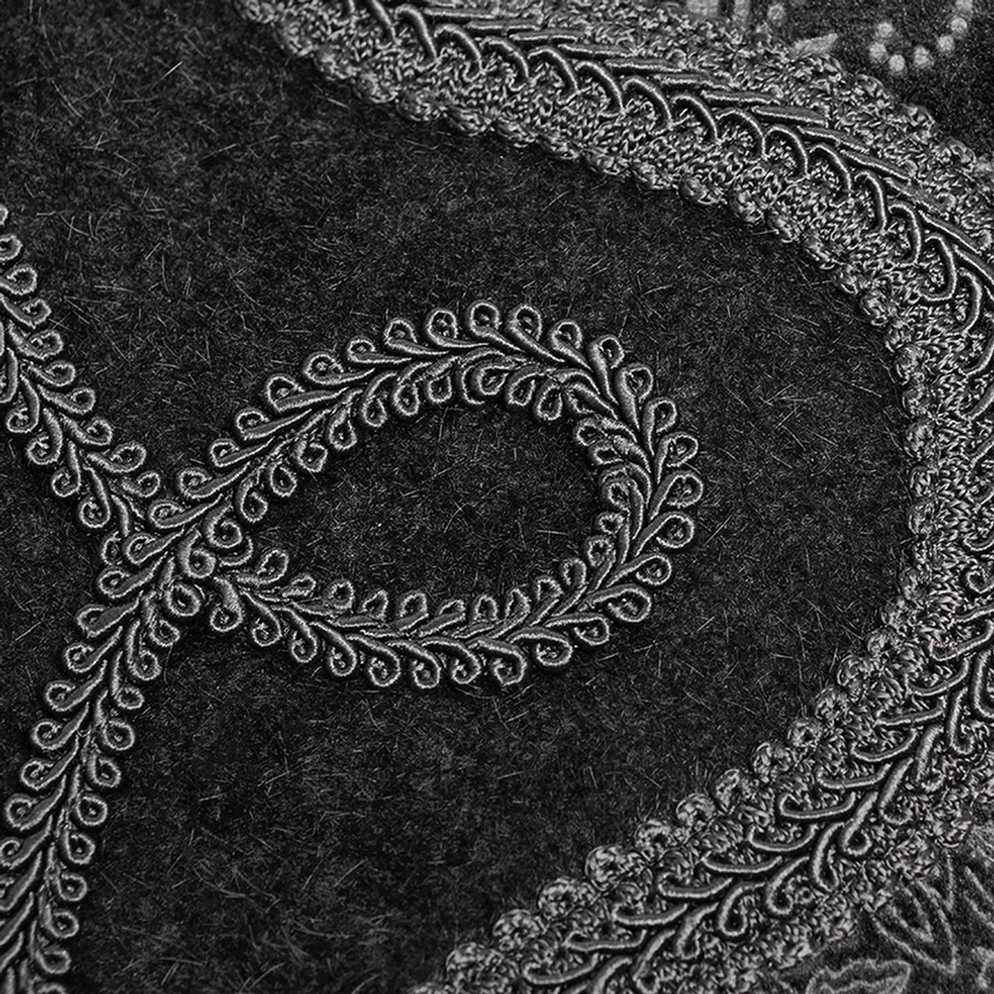 Bestickte Ranken-Gothic-Borte Detail Makroaufnahme, silberfarbene Stickerei auf schwarzem Samtstoff-Untergrund, verzierte Gothic-Bordüre, feine Textur und Handwerkskunst