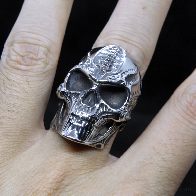 Silberner Metall-Totenkopf-Ring getragen am menschlichen Finger zeigt realistische geschnitzte Totenkopf-Details und tragbare gotische Schmuck-Anwendung