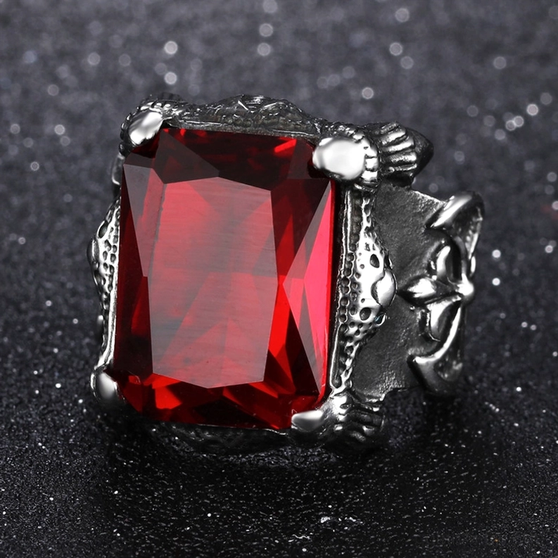 Frontalansicht Nahaufnahme des Blutrot-Zirkon Gothic Rings mit sichtbarer Kreuzgravur auf glanzvollem Silber-getöntem Edelstahl-Rahmen auf funkelndem Glitter-Hintergrund, zeigt maximale Edelstein-Brillanz