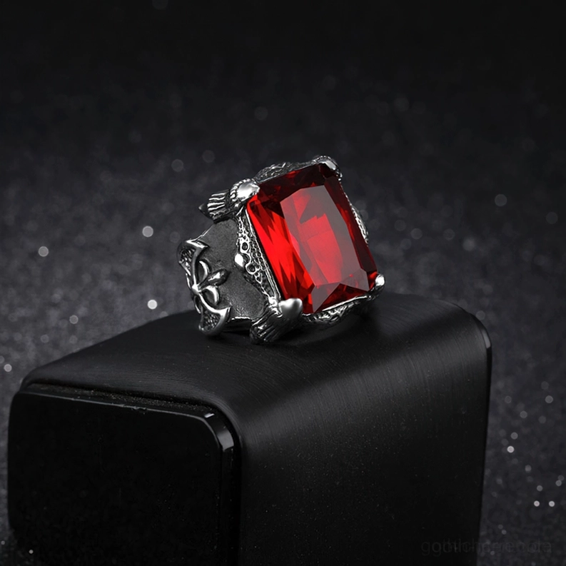 Seitenansicht des kompakten blutrot glänzenden Zirkon Gothic Rings auf schwarzem Schmuck-Ständer, zeigt leuchtenden facettierten roten Edelstein und ornamentales glänzendes Edelstahl-Rahmen-Design
