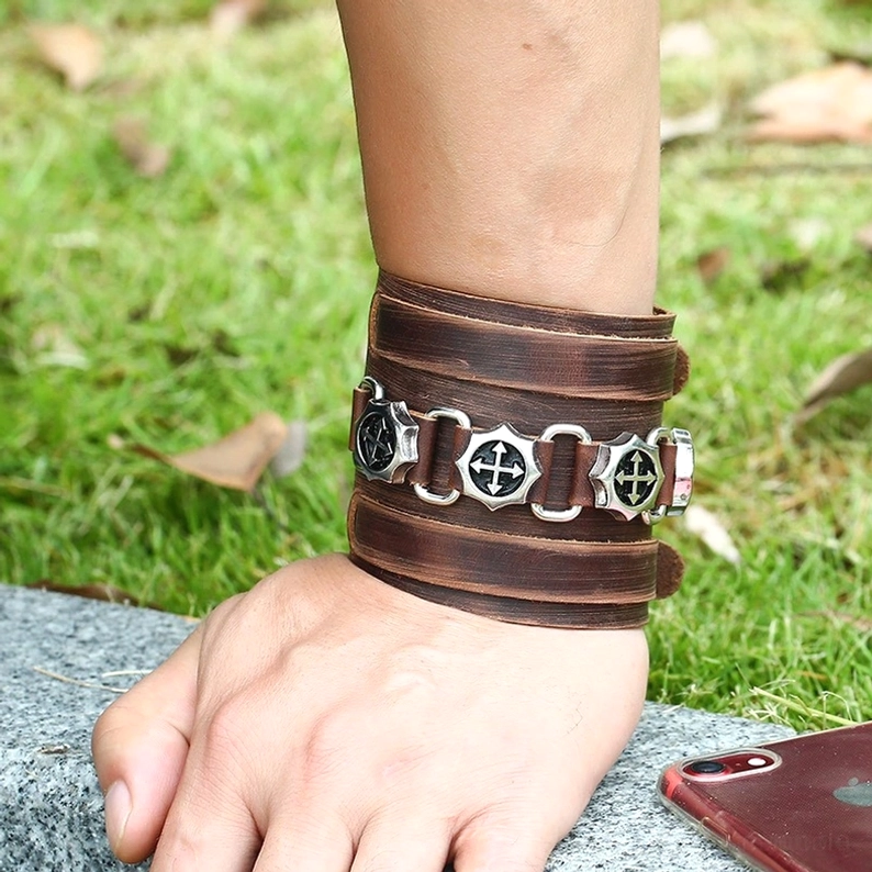 Braunes Leder-Gothic-Punk-Armband getragen am Handgelenk, echte Trageposition Outdoor-Szene auf Gras, Alternative Mode Styling