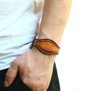 Breites braunes Leder-Armband Gothic mit gealterter Vintage-Oberfläche und Antik-Bronze-Hardware, getragen am männlichen Handgelenk, Seitenansicht zur Darstellung des Distressed-Finishs