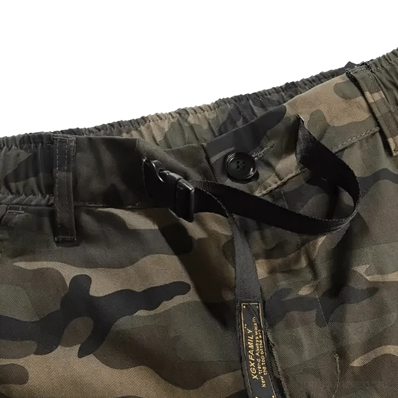Nahaufnahme der Taillenkonstruktion der Camouflage Cargo Hose, zeigt Knopfverschluss, verstellbares Nylon-Webband und Markenmarkierung