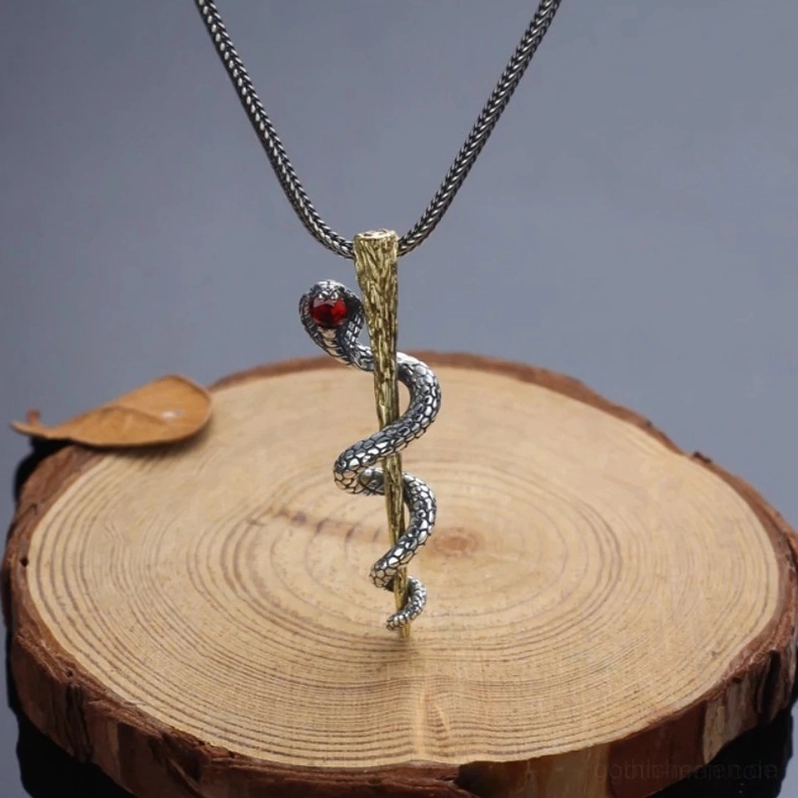 Kompletter Gothic Cobra Anhänger Halskette auf Holz-Display zeigt gedrehte Kette und rotes Rubin-Auge