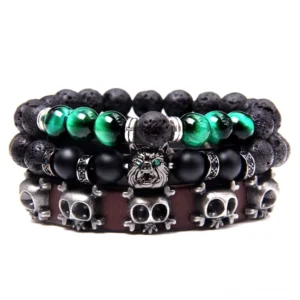 Dark Trinity Gothic Armband Stack – dreischichtige Naturstein Charm Bracelet mit Lava-Stein Perlen, grünem Tigerauge, mattschwarzem Stein, vintage oxidiertem Totenkopf und Bulldoggen Metall-Charm, braunem Leder auf weißem Hintergrund – Gothic Fashion Armband für Alternative Style