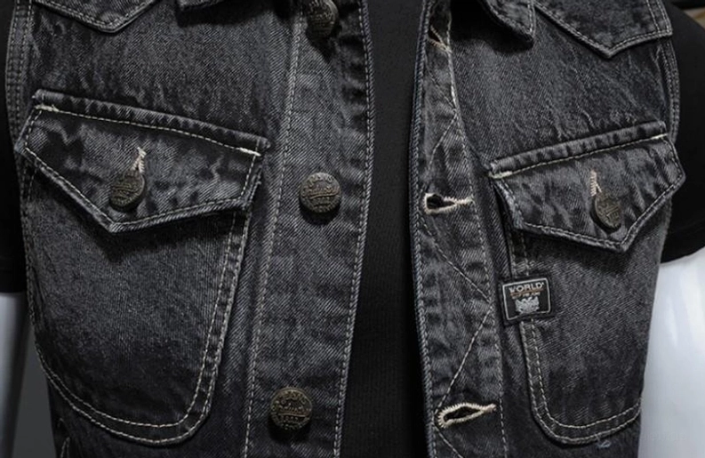 Extreme Nahaufnahme der Denim-Weste Knopfleiste zeigt Kontraststickererei, markierte Knopf-Hardware und Taschen-Etikett-Detail