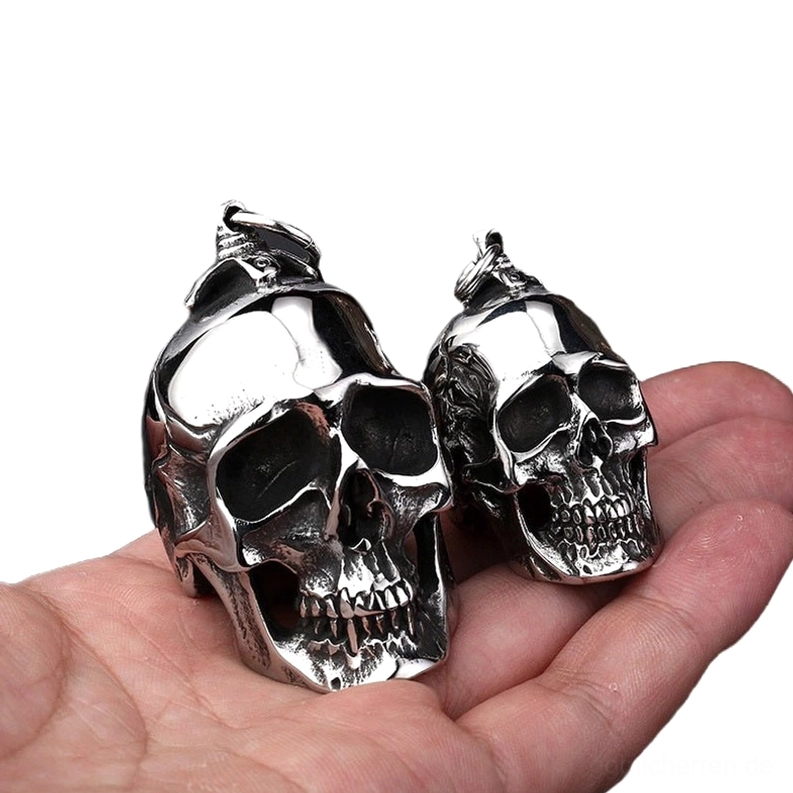 Zwei Größen Gothic Totenkopf-Anhänger aus poliertem Edelstahl auf Handfläche mit Größenvergleich für Memento Mori Halskette