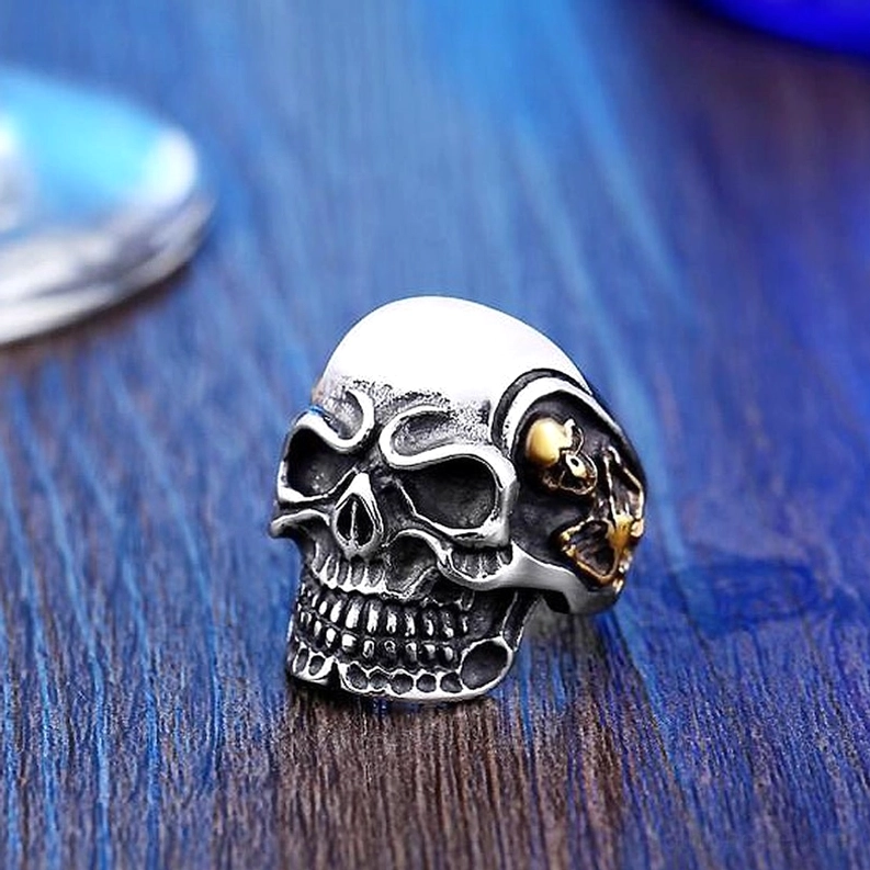 Dreifach-Totenkopf-Ring in Frontalansicht mit Schädel-Hierarchie-Komposition, zentraler dominanter Schädel, seitliche Begleit-Totenkopf-Symbole
