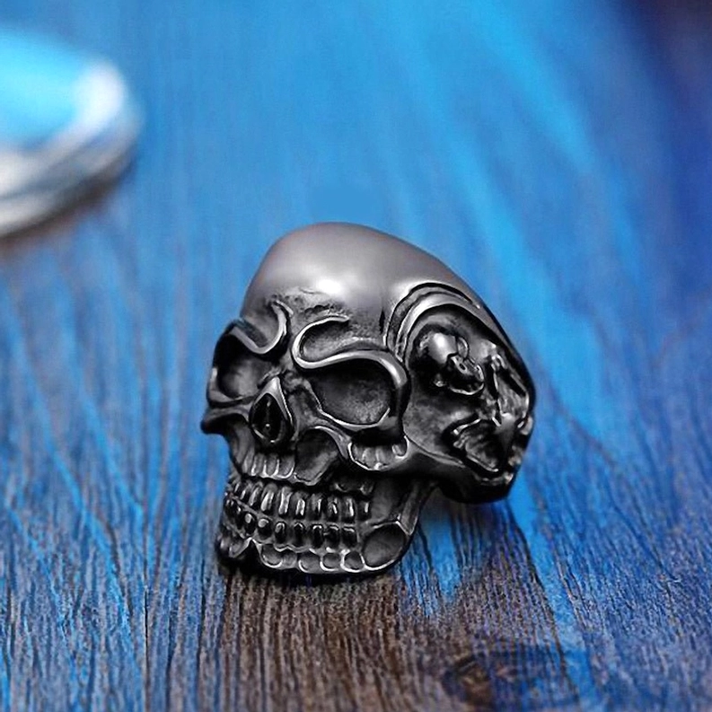 Matter schwarzer Dreifach-Totenkopf-Ring mit detaillierter erhabener Schädel-Textur, Seitenprofil-Nahaufnahme, Gothic-Handwerks-Detailansicht