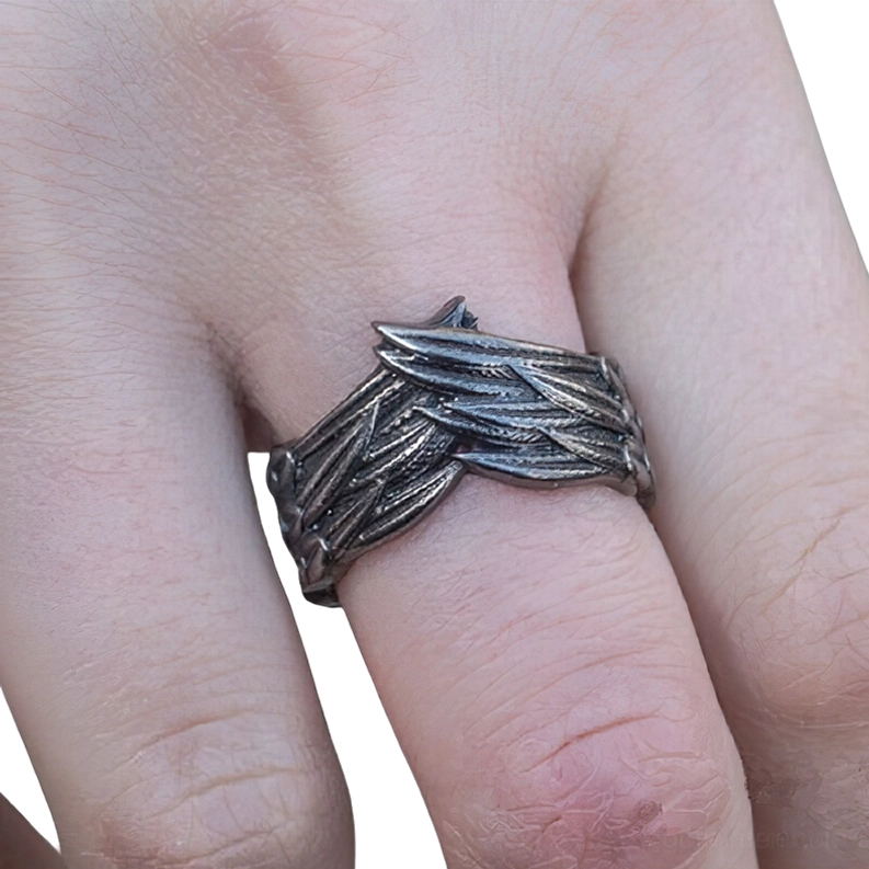 Dunkler Gothic Flügel Ring getragen am Finger mit feiner Federschnitzerei Detail in Frontalansicht, vintage dunkle Metalloberfläche sichtbar