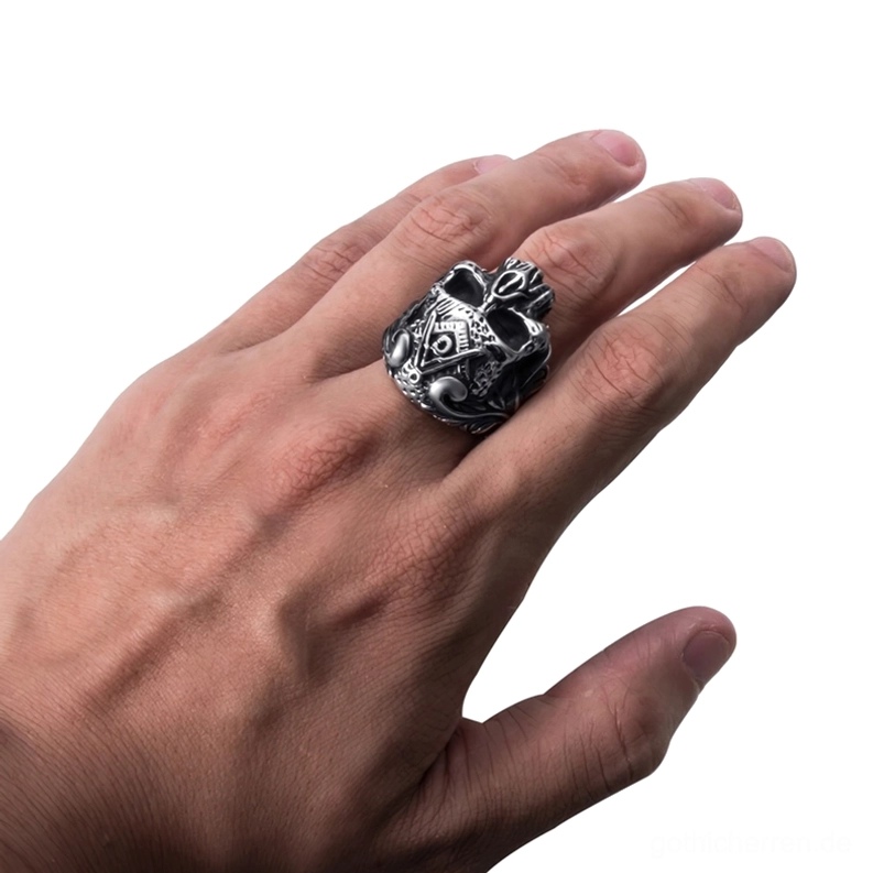 Maennerliche Hand traegt Freimaurer-Totenkopf-Gothic-Ring am Mittelfinger, zeigt perfekte Passform und gotischen Schmuck-Stil