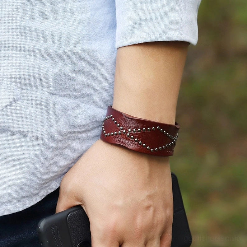 Echtes Rindsleder-Gothic-Armband mit industriellem Druckknopf-Schnallenverschluss und geometrischem Kreuznietermuster Detail und Texturaufnahme