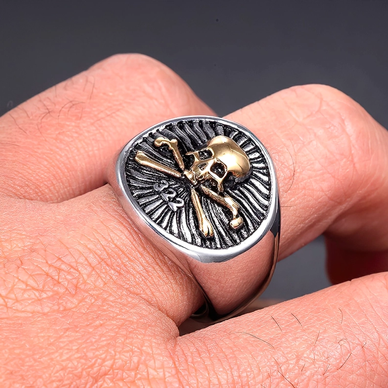 Goldener Totenkopf Crossbones Sigelring an männlichem Finger getragen, Seitennahaufnahme mit Details der radialen Textur