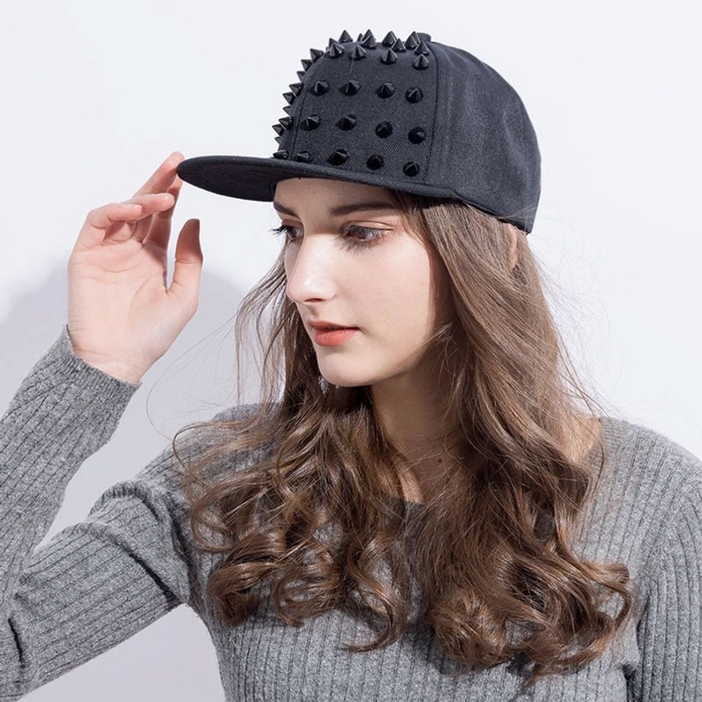 Modell trägt Gothic Spike Snapback Kappe aus linkem Winkel, alternative Fashion-Styling mit grauem geripptem Oberteil und Punk-Attitude