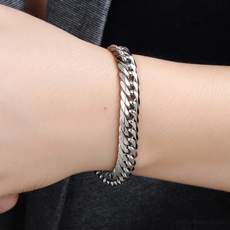 Männliches Handgelenk mit glänzendem silbernen Edelstahl-Gothic-Panzerarmband in Lifestyle-Aufnahme mit dunklem Anzug