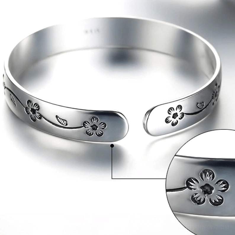 Nahaufnahme von oben des gotischen offenen Manschetten-Armbands mit innerer Markierung, polierte Silberoberfläche mit gravierten Blüten-Ranken-Design