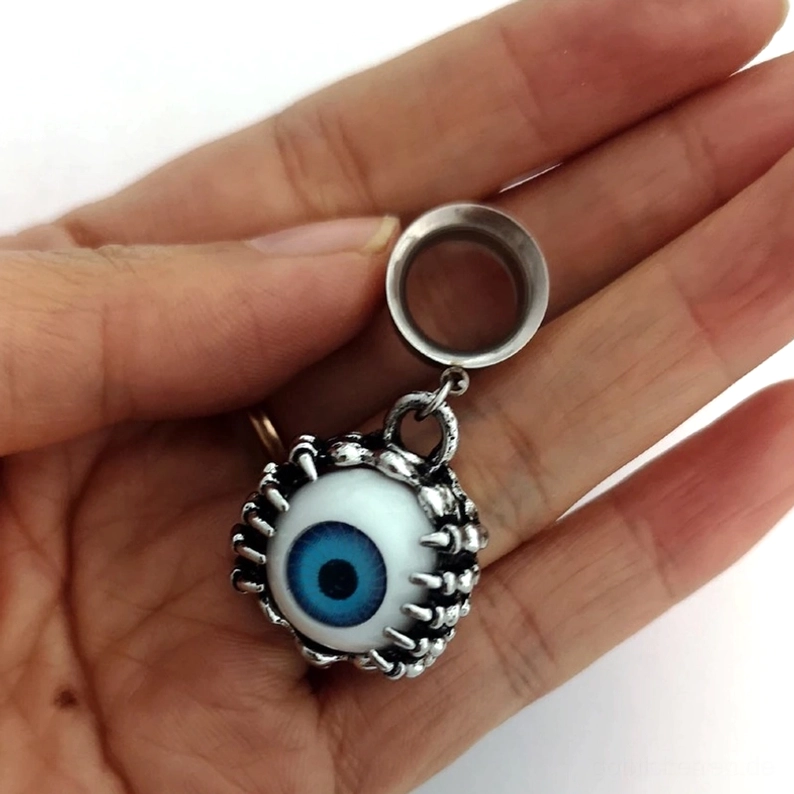 Einzelner gothischer Blauauge-Ohrtunnel in Hand gehalten aus Draufsicht-Winkel, zeigt das aufwendige Stachelrahmen-Design, silberne Politur des chirurgischen Edelstahls und die Tunnel-Konstruktion