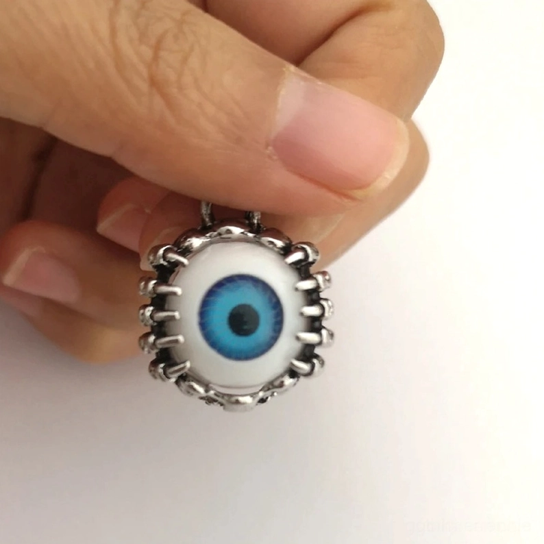 Nahaufnahme-Frontalansicht eines gothischen Blauauge-Ohrtunnels in Hand, zeigt lebendiges blaues Irisdetail, texturierten Stachelrahmen, chirurgische Stahlqualität und handverarbeitete Konstruktion