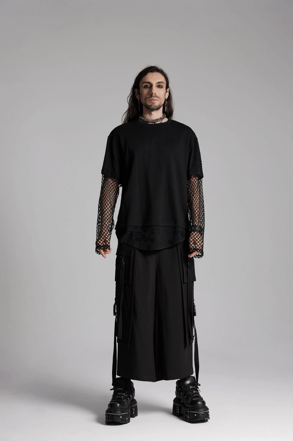 Vollständiges Styling-Showcase des männlichen Modells mit dunkelsilbernem Wirbelsäulen-Halsband, komplette schwarze Gothic-Outfit und dicke Plattformstieffel, Ganzkörperansicht