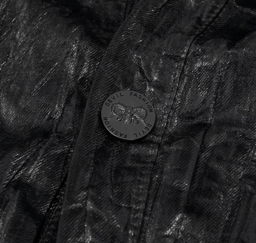 Nahaufnahme des gestanzten Markenknopfes auf dem Crinkle-Kunstlederstoff des Gothic Hemdes mit Schädelmotiv