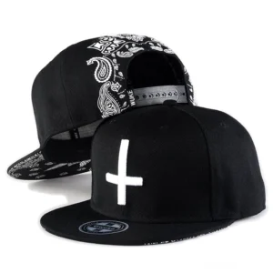 Schwarze Gothic Cross Snapback Kappe mit weißer Kreuzstickerei von vorne und seitlich, Paisley-Muster auf der Rückseite, Alternative Baseball-Kappe mit flacher Krempe