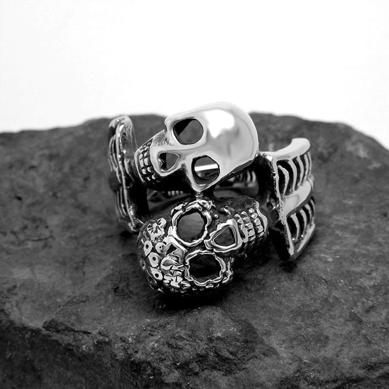 Punk-Gothic Doppelschädel Ring – Draufsicht zeigt kontrastreich polierte und gravierte Schädel mit dunkelgeschwärzter Patina auf Edelstahl, Stone-Hintergrund