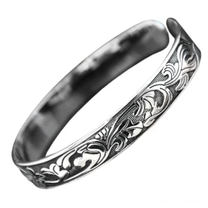 Vintage ornamentales Silber-Bangle-Armband mit geschnittenen Ranken- und Blütenmotiven – Draufsicht-Detailaufnahme des geprägten Designs und der offenen Manschettenkonstruktion