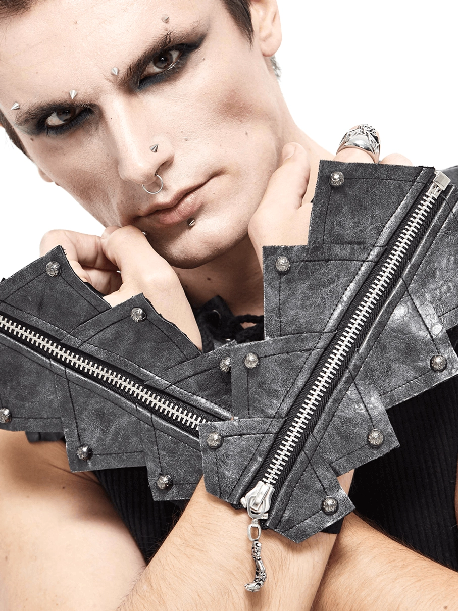 Gothic männliches Model mit schwarzen fingerlose Handschuhe mit Totenschädel-Reißverschluss, dunkles Make-up und Goth-Ästhetik mit Metallnieten-Details im Studio