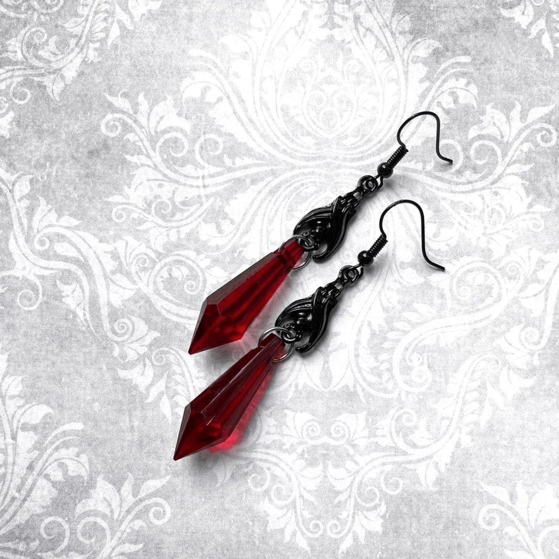 Schwarze Filigran Fledermaus Ohrringe mit roten facettierten Tropfen-Charms auf vintage Damast Stoff Hintergrund - gotische Schmuck Ästhetik