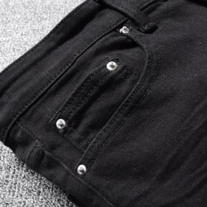 Nahaufnahme des Taschenschnitts schwarzer Denim Biker Jeans mit Metall-Nieten und verstärkten Nähten, funktionale Taschenbordüre für gotische Alternative Wear mit silbernen Hardware-Details