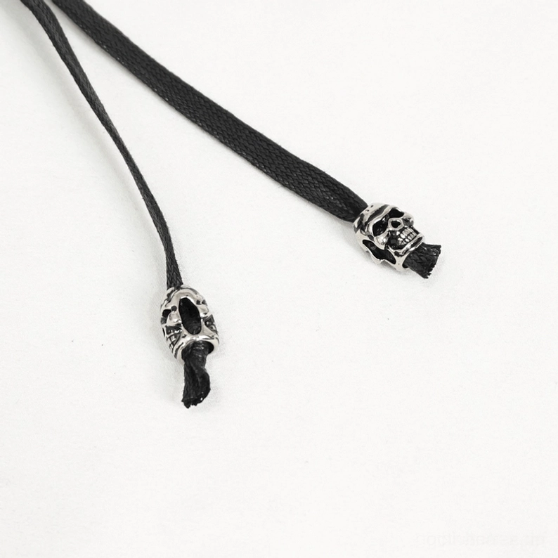 Nahaufnahme von oben des Totenkopf-Charm-Zugstrang-Details und Metalverzierungen auf gotischem Punk-Gürtel, Close-Up-Produktfotografie