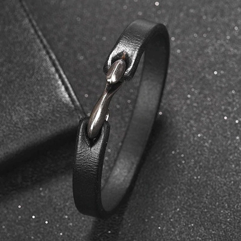 Seitennahaufnahme des schwarzen Lederarmbands, Bootshaken-Verschlussmechanismus, vintage Metalldetail close-up