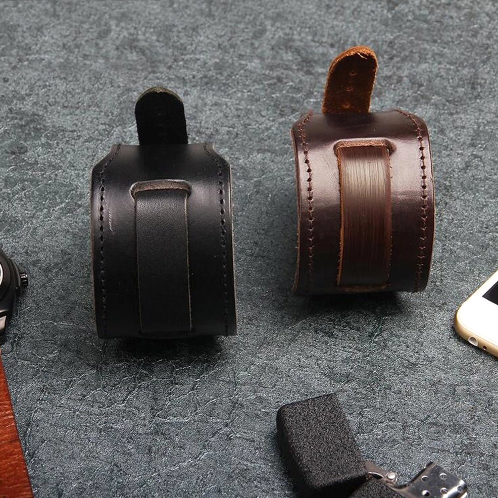 Flache Ansicht Vergleich von schwarzem und braunem echtem Leder Gothic Armband auf dunkler strukturierter Oberfläche mit Feuerzeug und Smartphone für Größenvergleich