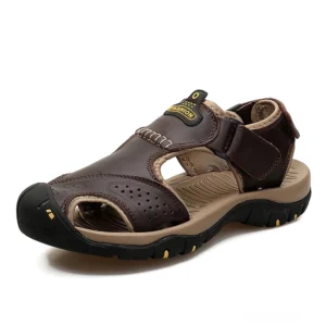 Dunkle braune Echtleder gothic Knöchelriemen-Sandalen mit perforiertem Obermaterial und verstellbarem Klettverschluss in Drei-Viertel-Vorderansicht auf weißem Hintergrund