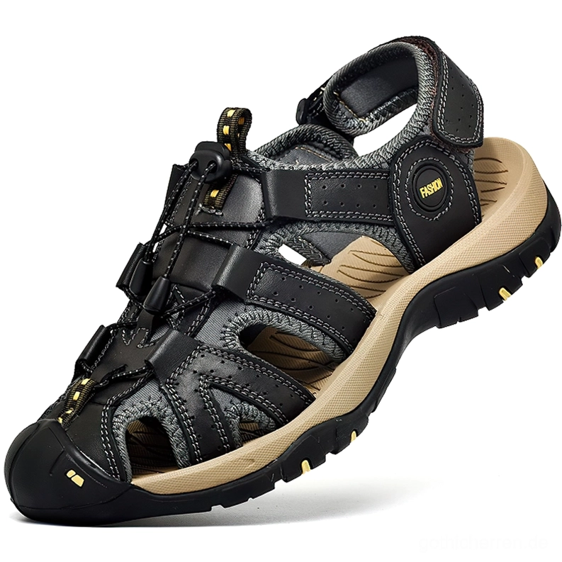 Schwarze gotische Ledersandalen für Herren mit Knöchelriemen, Dreiviertelvorderansicht mit geschlossener Zehenpartie und griffiger Gummilaufsohle