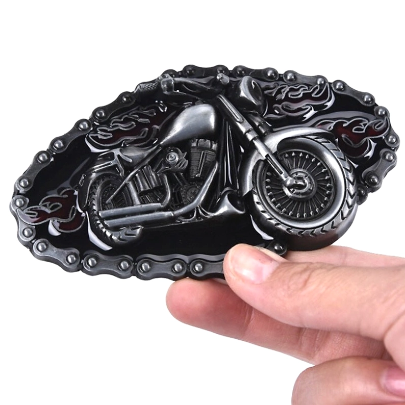 Hand hält Gothic Motorrad Gürtelschnalle – Schräge Handgriff-Perspektive der geprägten Chopper-Motorrad mit Flammen-Akzenten und ornamentaler Ketteneinfassung