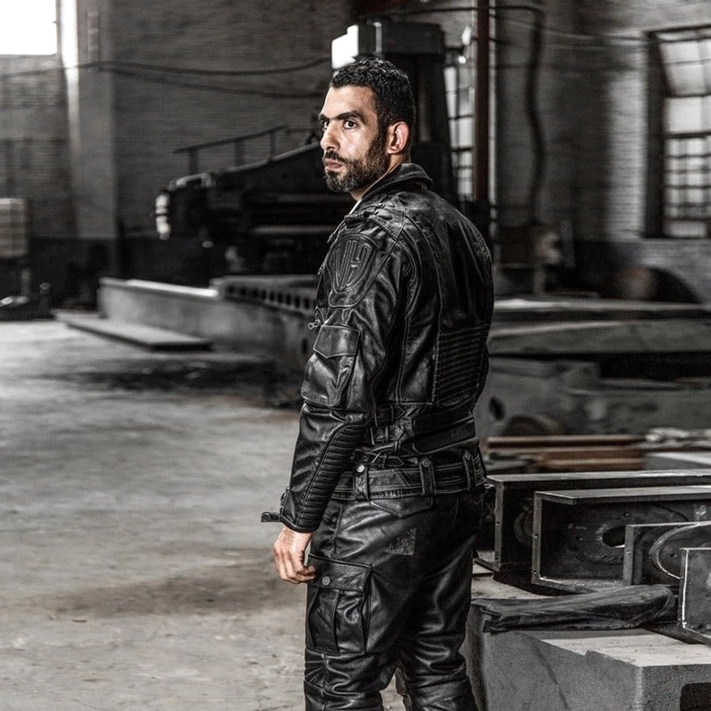 Herrenmodell trägt schwarze echte Leder Gothic Motorradjacke, Seitenprofil-Aufnahme, detaillierte Stepp-Nähte sichtbar, Metallhardware-Details, stehendes Pose-Profil