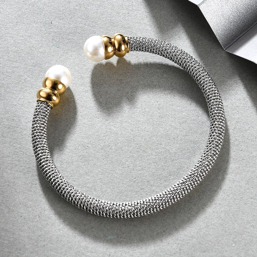 Offenes Cuff Gothic Armband mit geflochtenem Edelstahl und weißen Perlen auf grauem Hintergrund