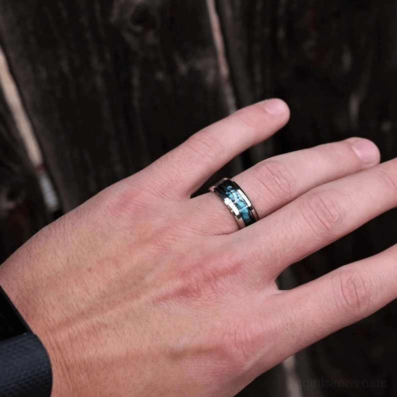 Unisex Perlmutt-Intarsia Edelstahl Gothic Ring getragen an männlicher Hand mit irisierendem Muscheldetail gegen dunklen Holzuntergrund