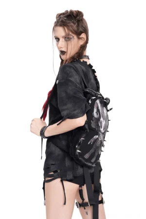 Schwarzer Gothic Rucksack mit Dämonenmotiv, Hörnern und Nieten in seitlicher Trageansicht zu düsterem Punk-Goth Outfit