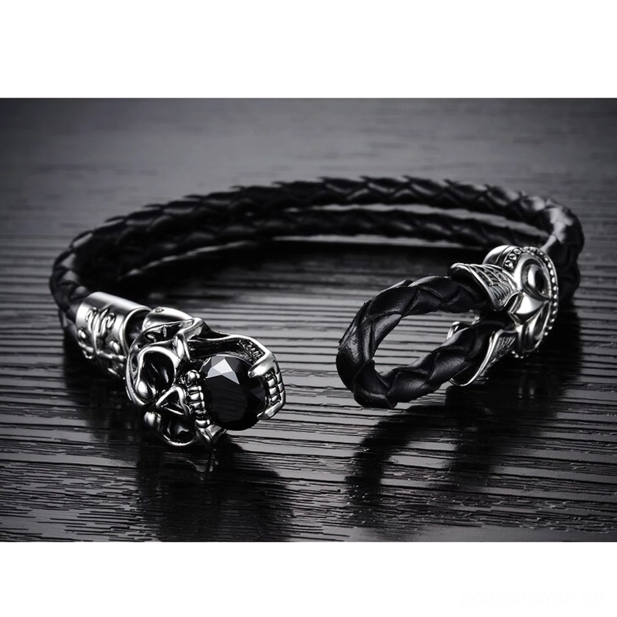 Offenes Gothic Schädel Lederarmband mit Hakenverschluss auf dunkler Holzoberfläche – Flachlage-Produktansicht zeigt Verschluss-Mechanismus und geflochtenes Leder