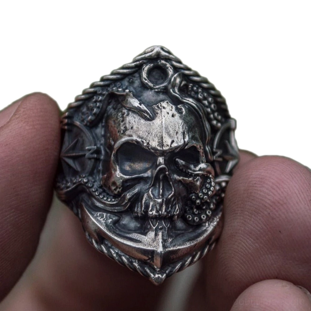 Gothic Schädel Anker Kompass Ring an männlichem Finger getragen, zeigt geschnitzte details und verwittertes finish in nahaufnahme