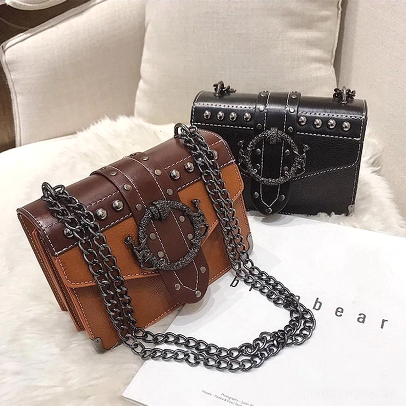 Zwei Gothic Schultertaschen in Tan-Braun und Schwarz auf flauschigem weißem Kissen mit Modemagazin, Kettenkette-Details und Nieten-Verzierungen sichtbar, Lifestyle-Flat-Lay-Fotografie