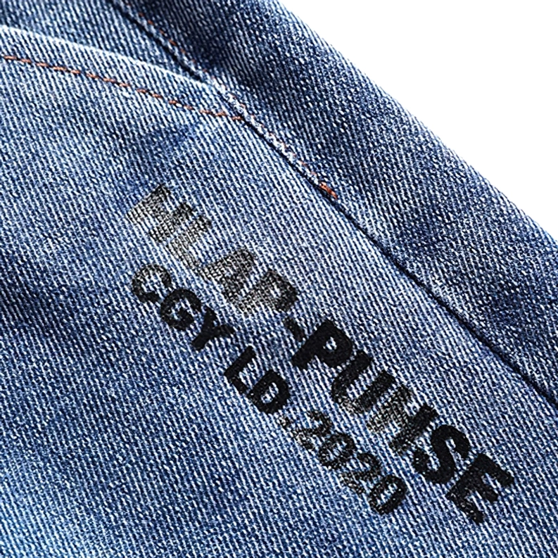 Detaillierte Nahaufnahme des geprägten Letter-Prints auf dunklem Denim Shorts-Stoff mit sichtbarer Stickerung und Köper-Weave – Geprägter Gothic Print Detail