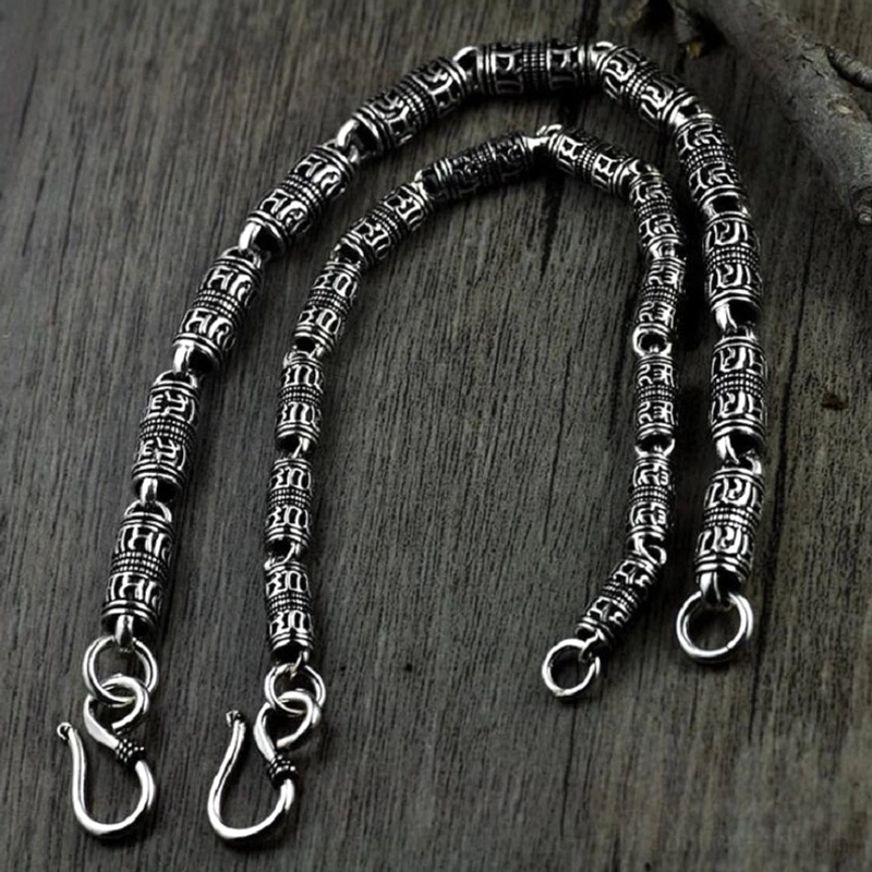 Paar passende Gothic Silberarmbänder mit gravierten zylindrischen Perlen, Draufsicht auf dunklem Holzuntergrund, verwitterter Vintage-Look, okkulte Schmuckkollektion