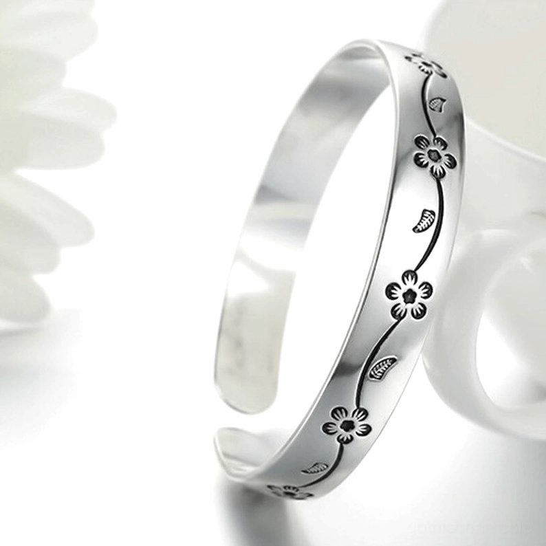 Vintage-Silber-Gothik-Armband mit oxidierten Blüten- und Blattelementen neben Keramiktasse, stilisierte Flachlage-Fotografie
