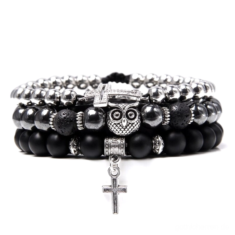 Silberfarbenes gotisches mehrschichtiges Armband mit schwarzem mattem Lavastein, Eulencharm, baumelndem Kreuzanhänger, Natursteinen und mystischen Metallakzenten, flache Produktfotografie