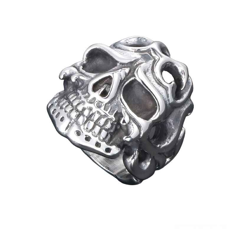 Draufsicht des antik-silbernen Skull Edelstahlrings mit Tribal-Design, zeigt detaillierte Schädelzähne und Hohlschnitte aus schräger Perspektive auf weißem Hintergrund