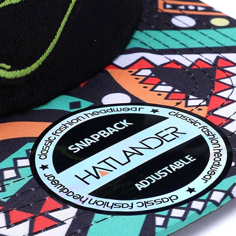 Draufsicht-Nahaufnahme schwarze Snapback Cap mit geometrisch bedrucktem Krempen-Muster und verstellbarem Kunststoff-Snapback-Verschluss im Detail